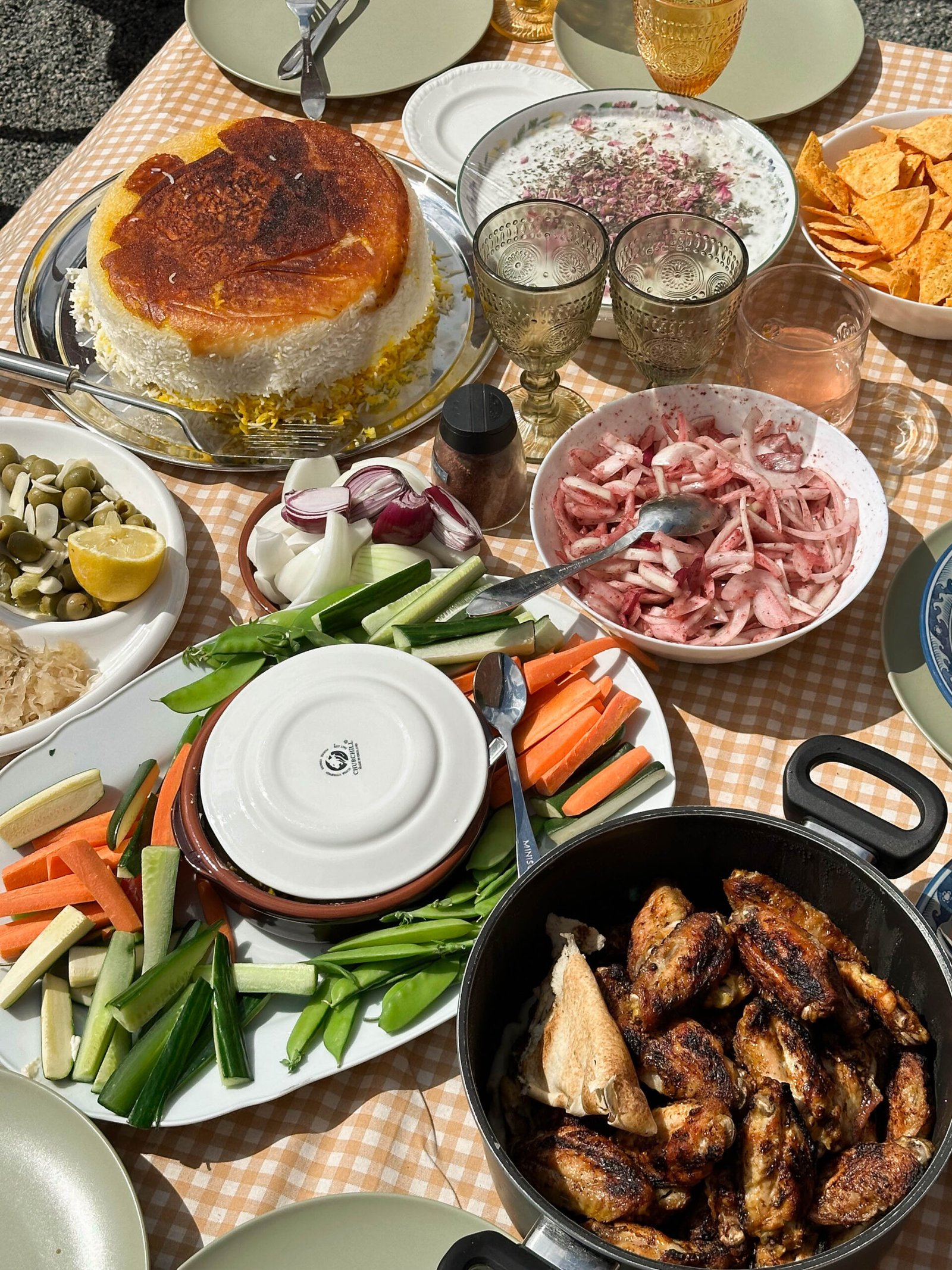 A vibrant family spread at a Persian manghal party, featuring a variety of dishes including kababs, rice, salads, and an array of colorful side dishes, set on an outdoor table.