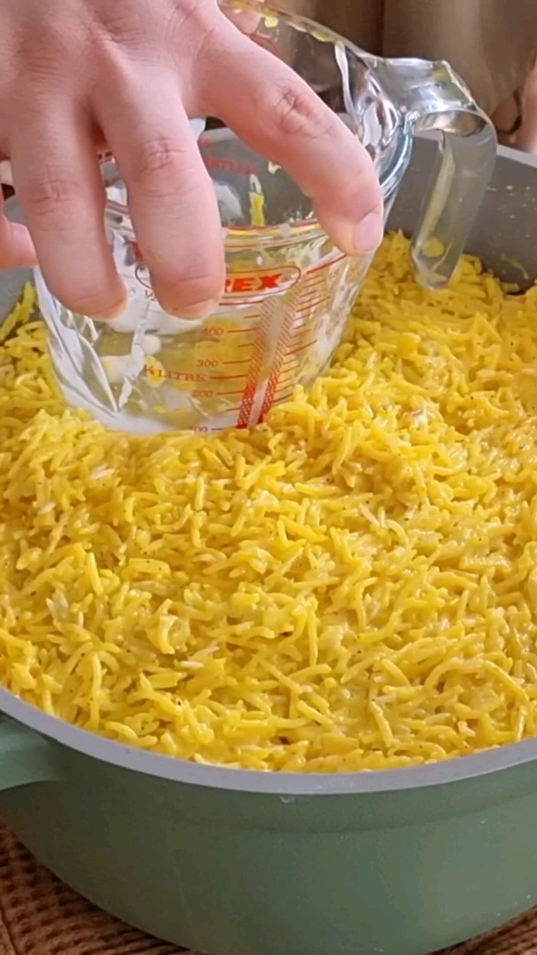 Flatten the top saffron rice layer using Pyrex jug