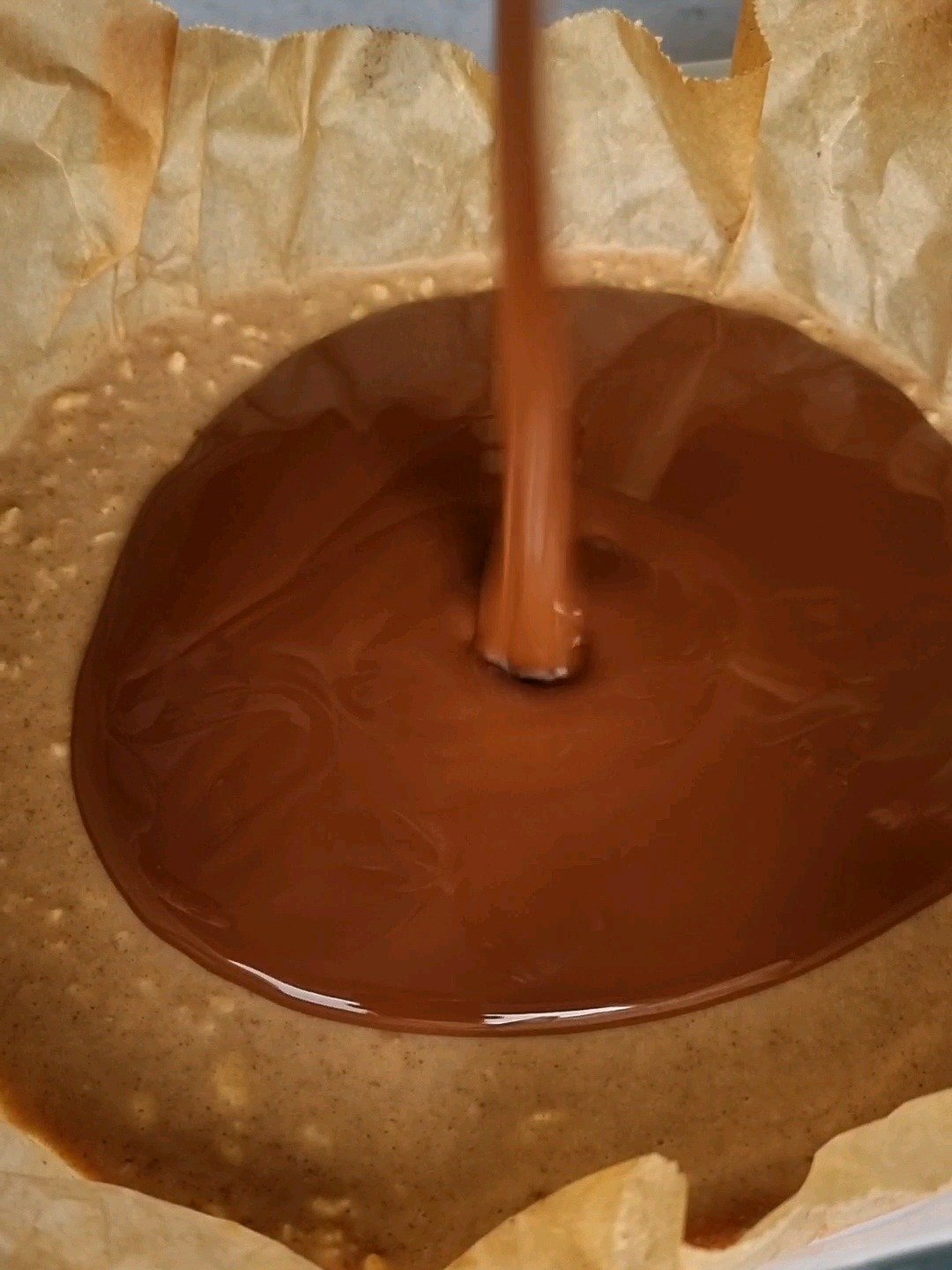 Pouring the melted chocolate on top of peanut butter