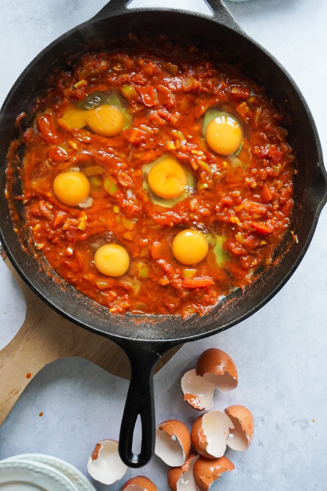 As soon as the tomatoes have become soft and the water has dried up, make little wells in the mixture and crack the eggs one by one into the wells. Put the lid back on so the eggs can cook and harden. Serve up and enjoy!