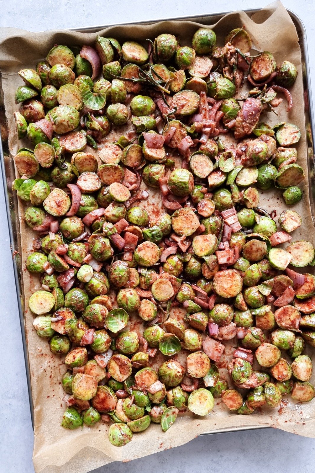 Brussels sprouts laid on a baking tray with other chopped veggies