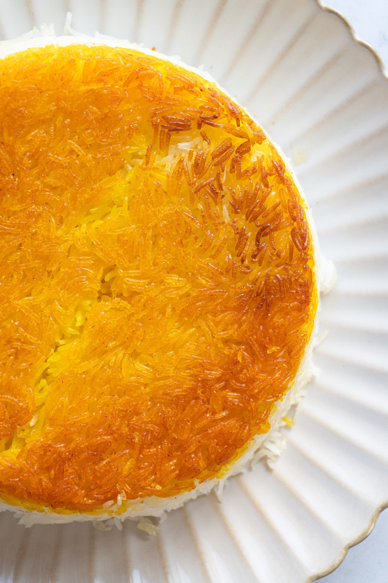 A close-up image of a Persian Saffron Rice With Tahdigg, crispy and golden, showing the crispy exterior and fluffy interior of the rice dish.