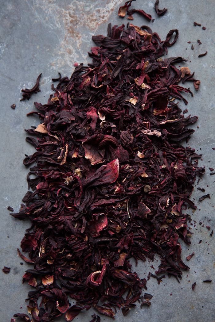 Close-up image of dried hibiscus flowers, showcasing their deep red color and crinkled texture, ready for making karkade (hibiscus tea)