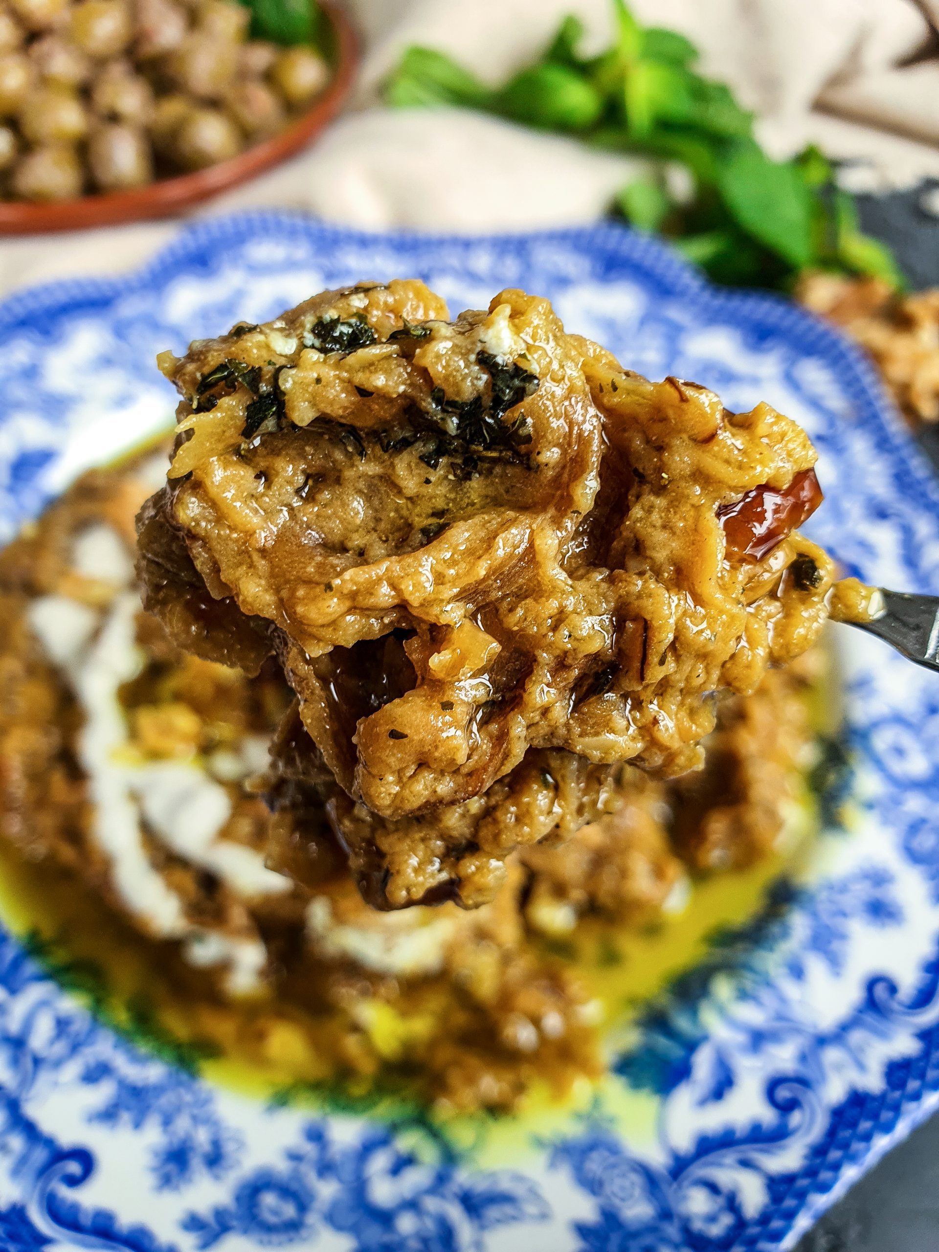 A spoonful of the traditional Iranian dish, Kashke Bademjan, filled with a mixture of grilled eggplant, kashk, garlic, and onion, topped with sautéed tomatoes and fried mint leaves