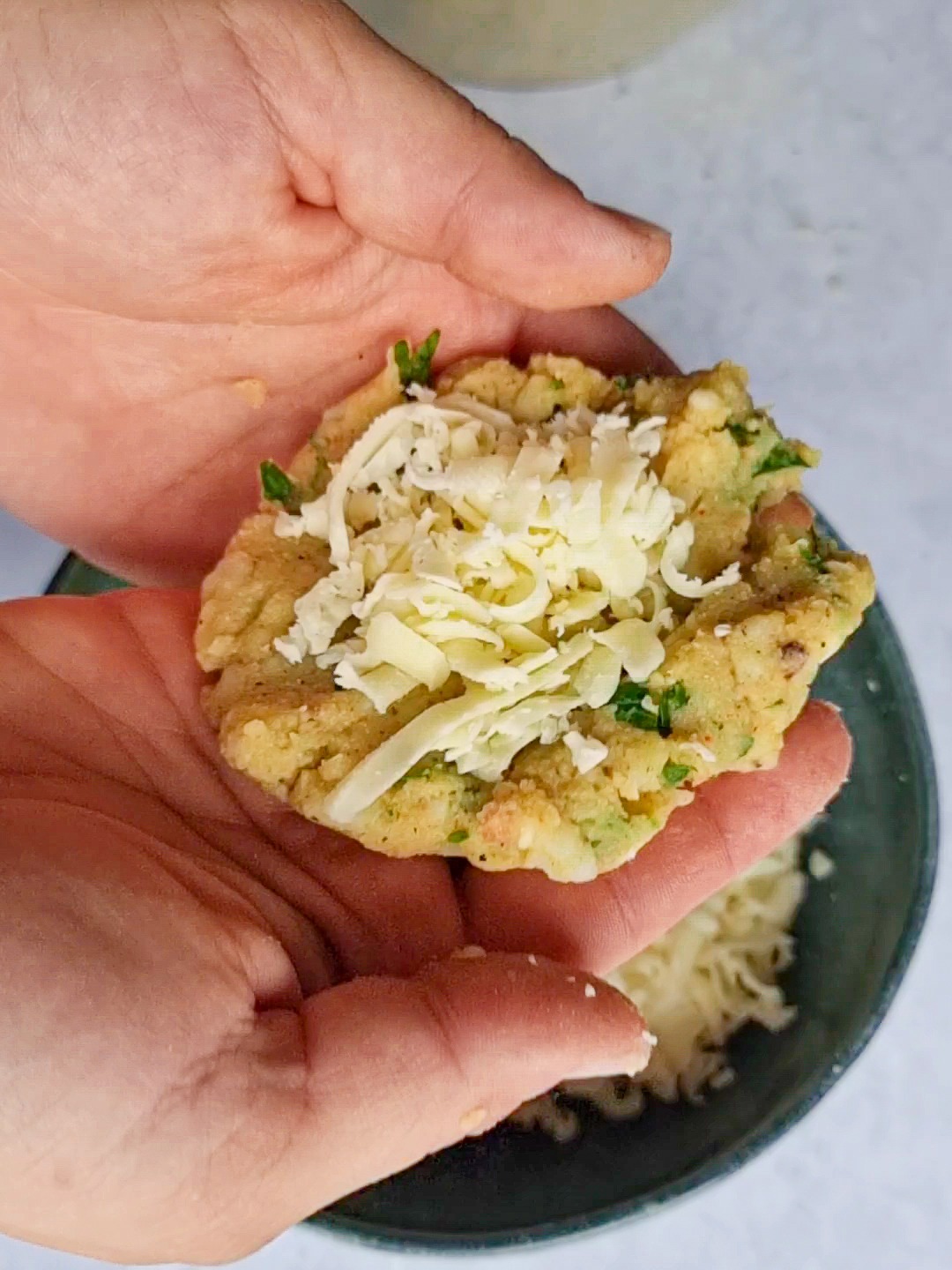 Adding shredded mozzarella to potato patties to get delicious cheesy kuku Sibzamini