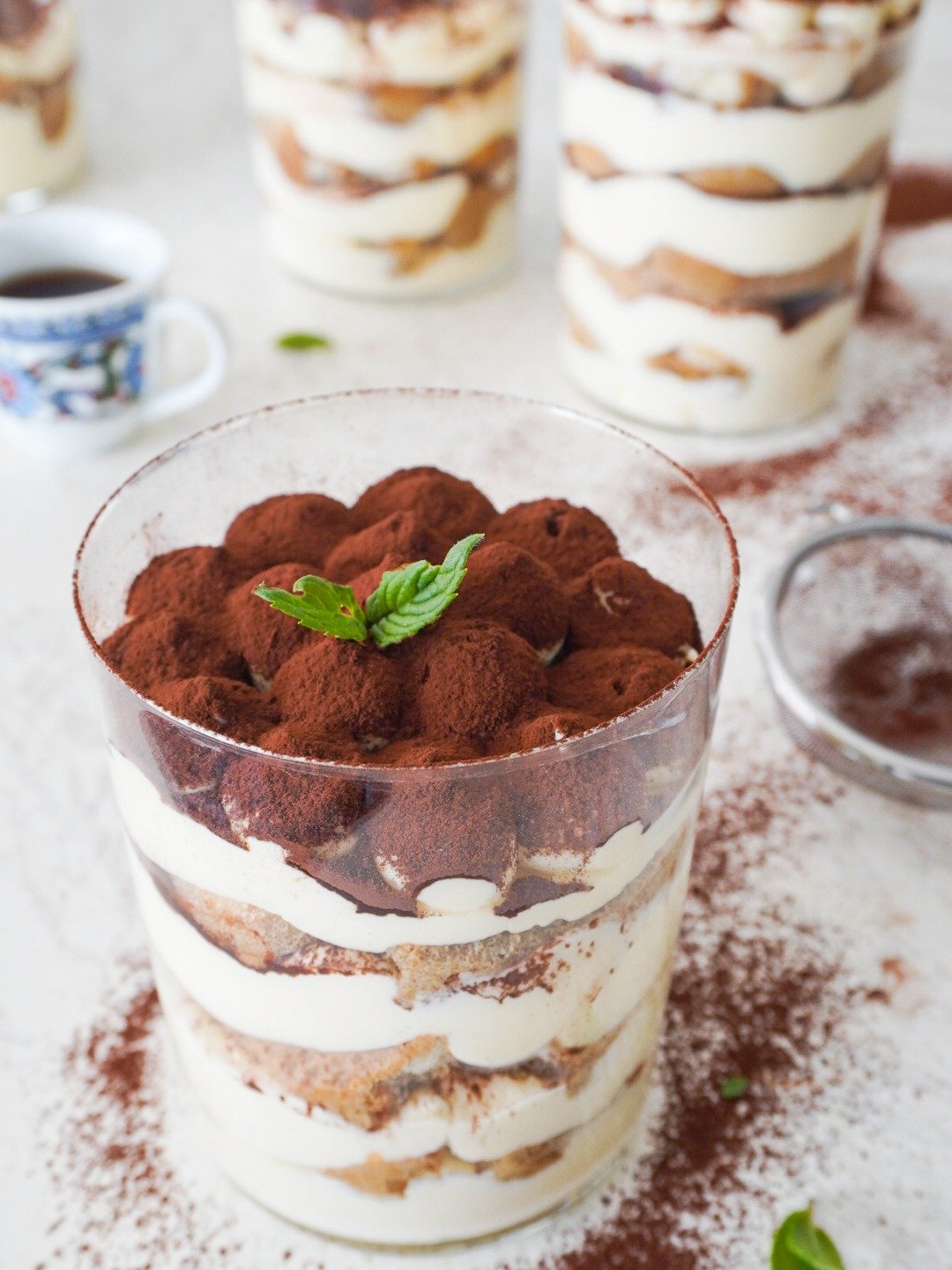 A cup of layered ladyfingers and cream topped with cacao powder