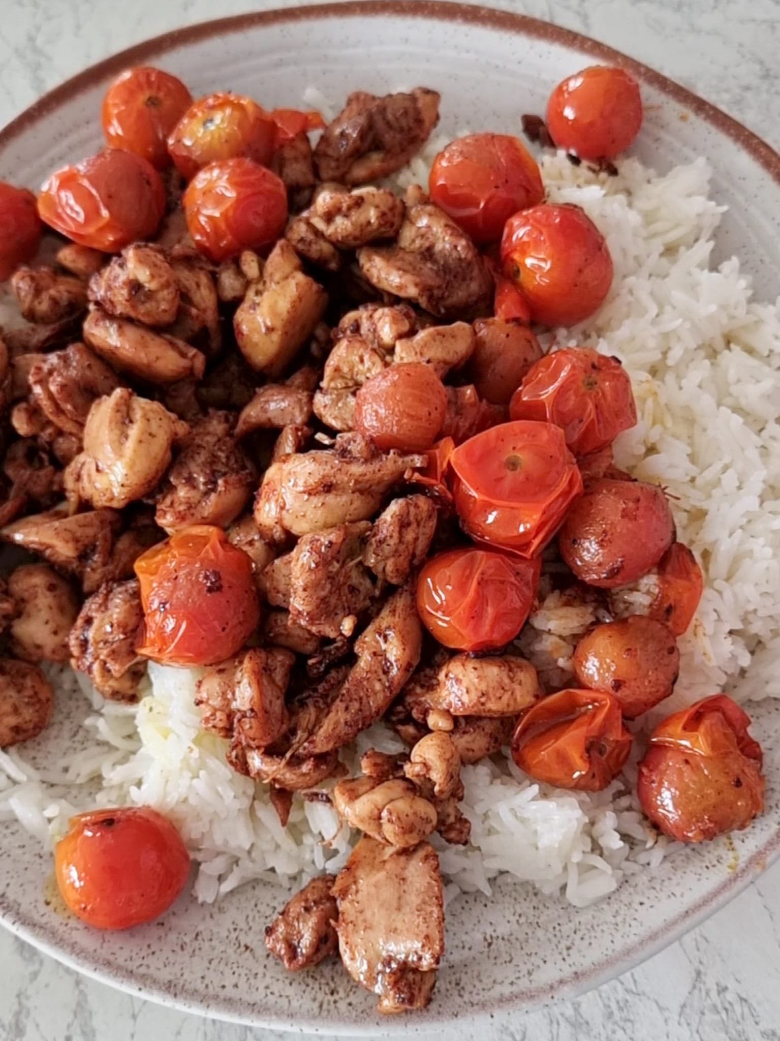 Sumac Chicken served with steamed rice and pan fried cherry tomatoes
