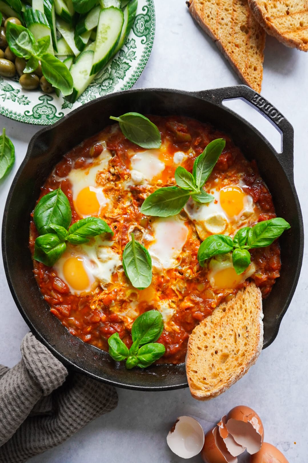 Deliciously tasting Shakshuka garnished with fresh mint or basil and a side of sourdough bread. 