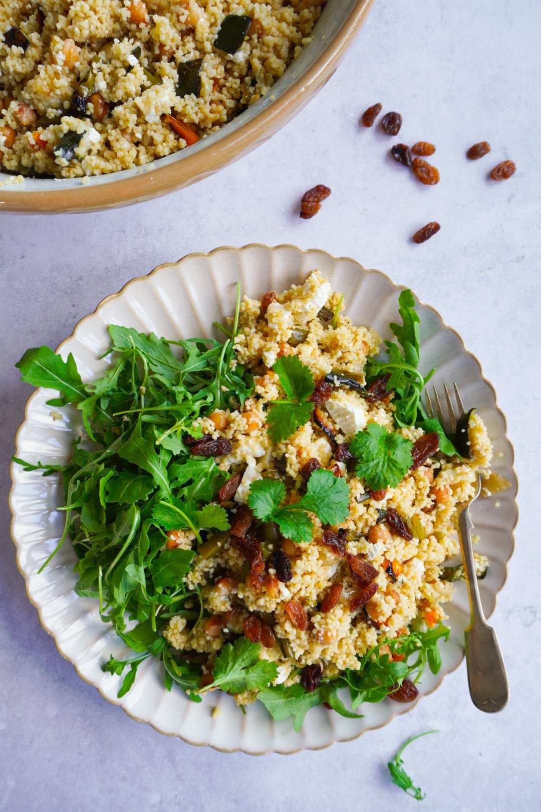 Quick and easy roasted vegetables couscous salad topped with arugula and sultanas