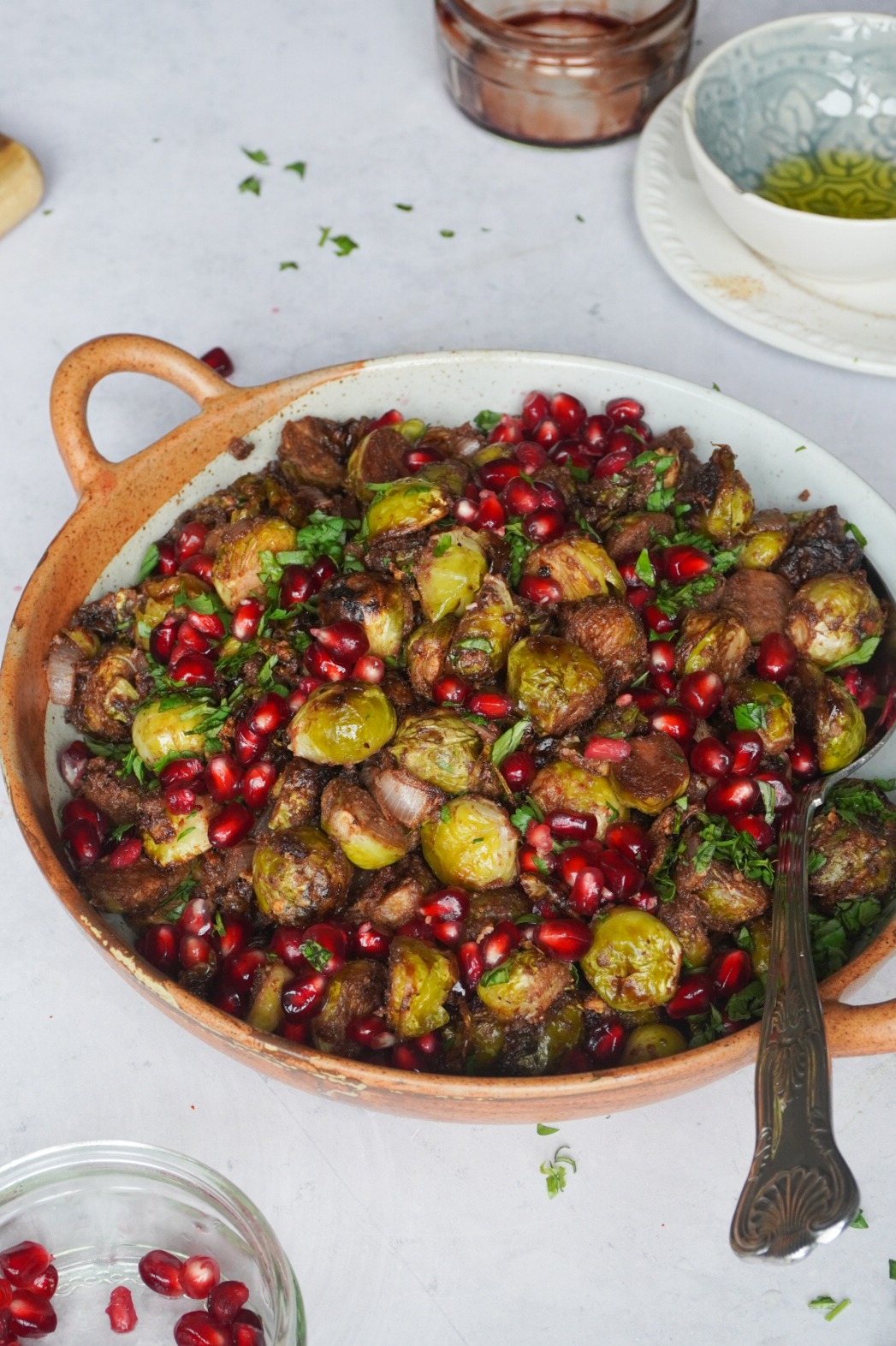 Middle Eastern Tahini and pomegranate brussels sprouts served with pomegranate seeds and chopped coriander 