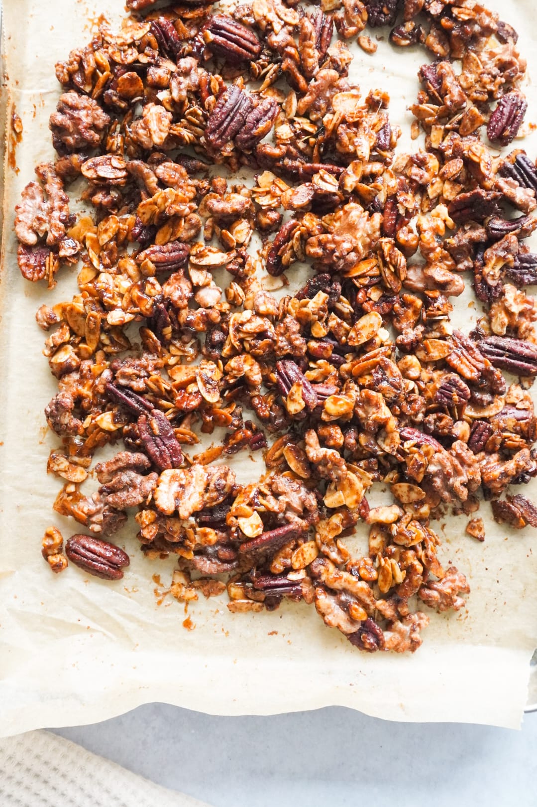 Mixed glazed nuts on the parchment paper on the tray.