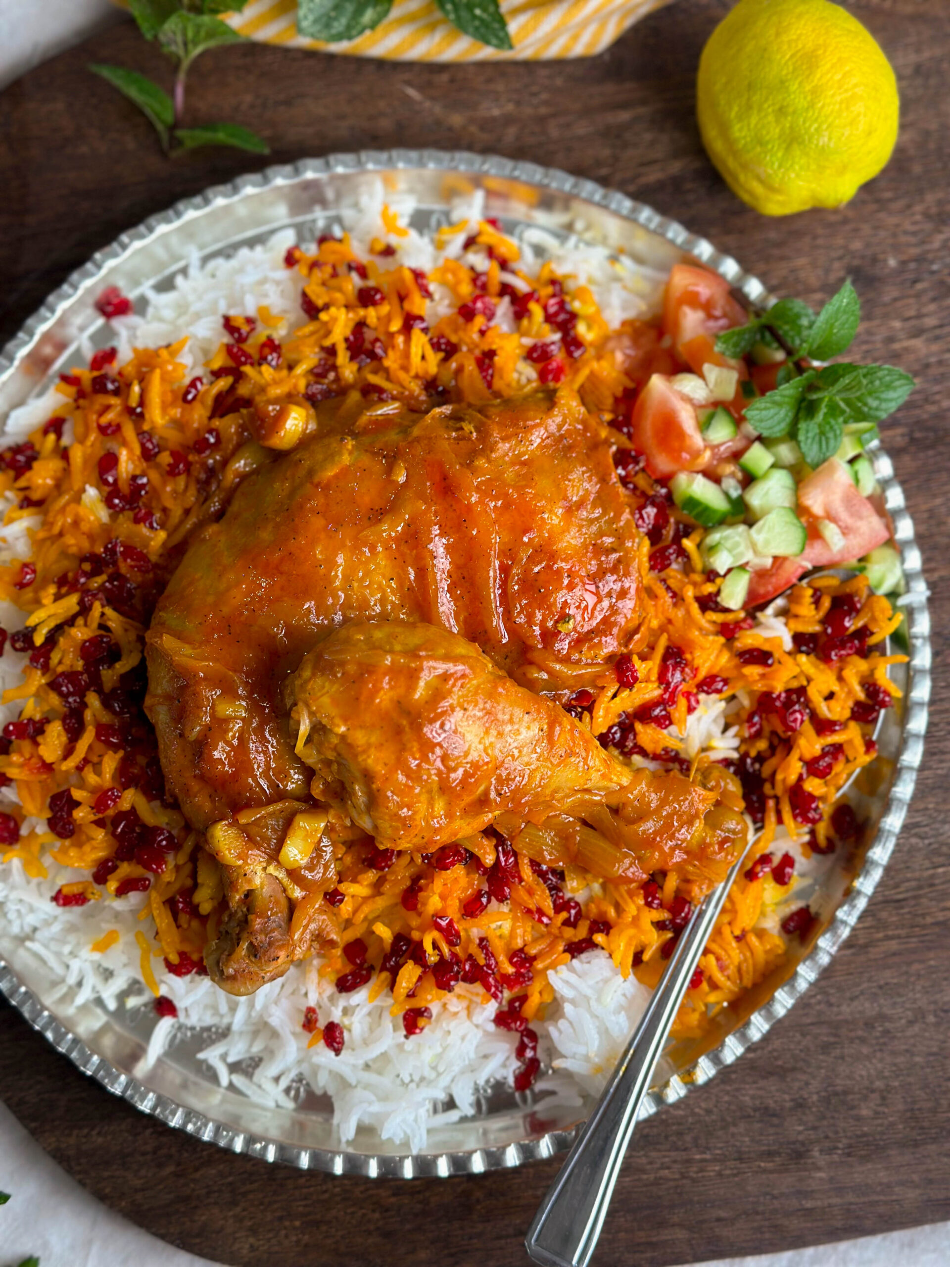 A beautifully arranged plate of Zereshk Polo Morgh, showcasing the tender chicken, fluffy rice, and bright red barberries.