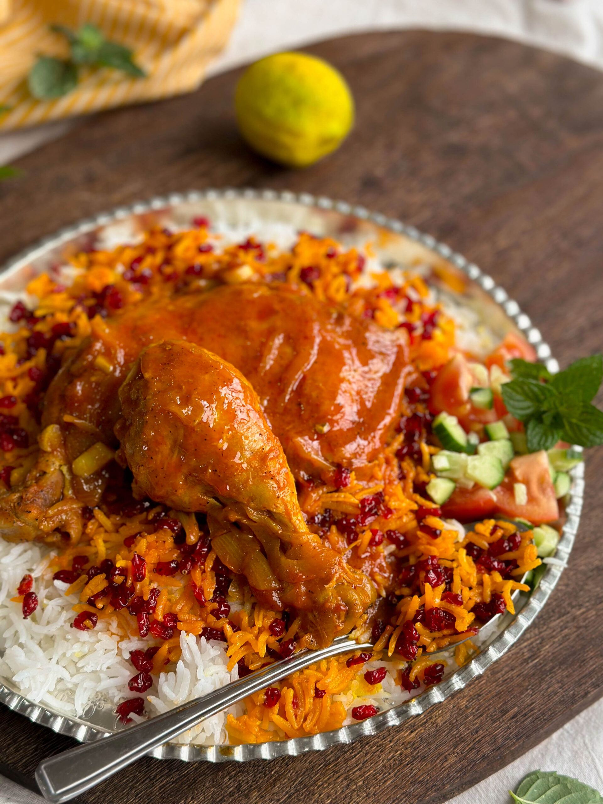 A beautifully arranged plate of Zereshk Polo Morgh, showcasing the tender chicken, fluffy rice, and bright red barberries.