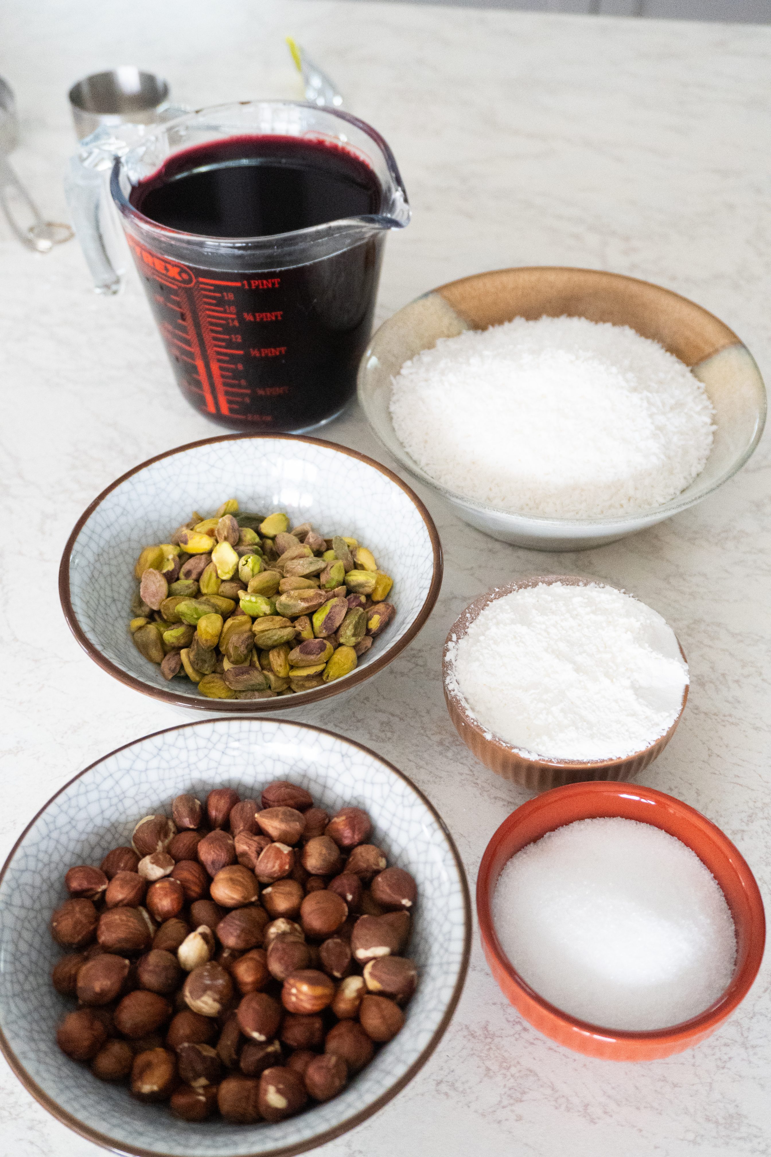 A close-up image of a selection of Turkish Delight ingredients including sugar, rose water, corn starch, nuts and desecated coconut.