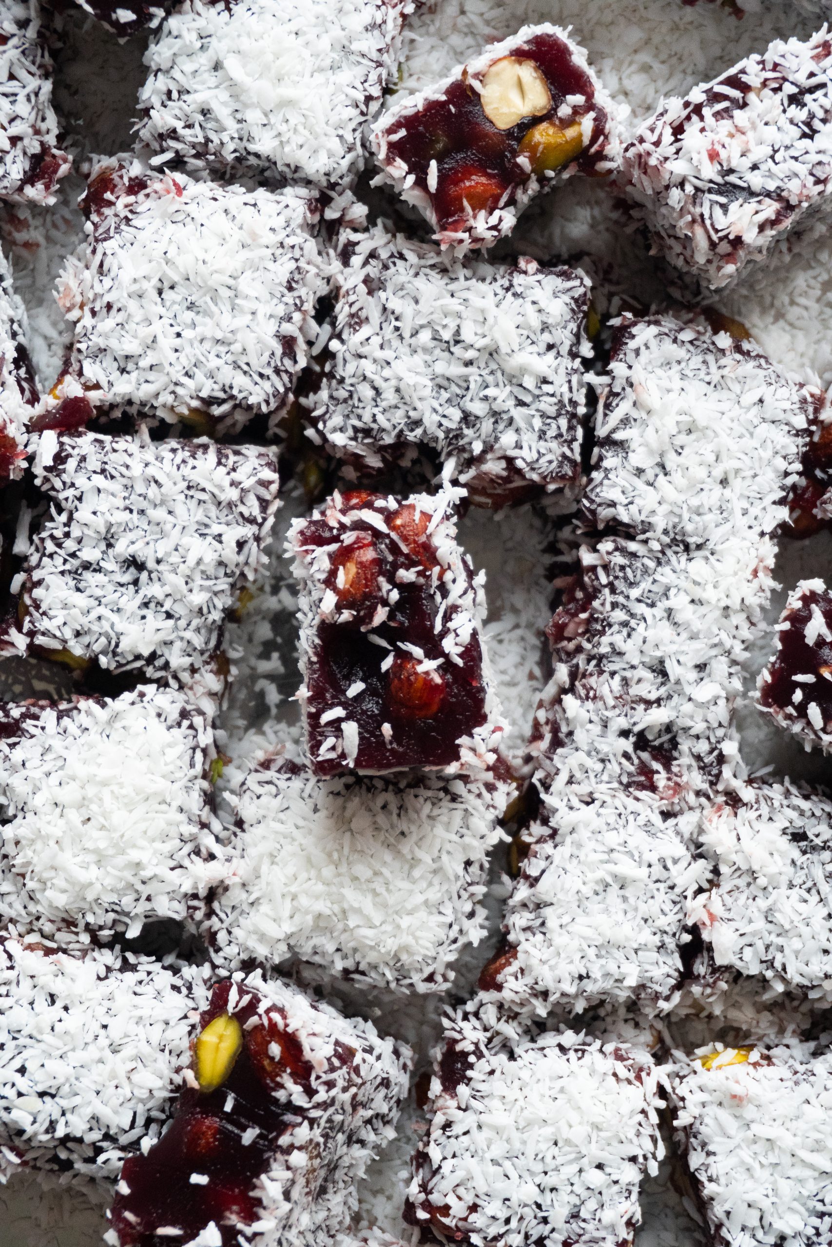 A close-up shot of pomegranate Turkish Delight squares with a juicy and vibrant red filling.