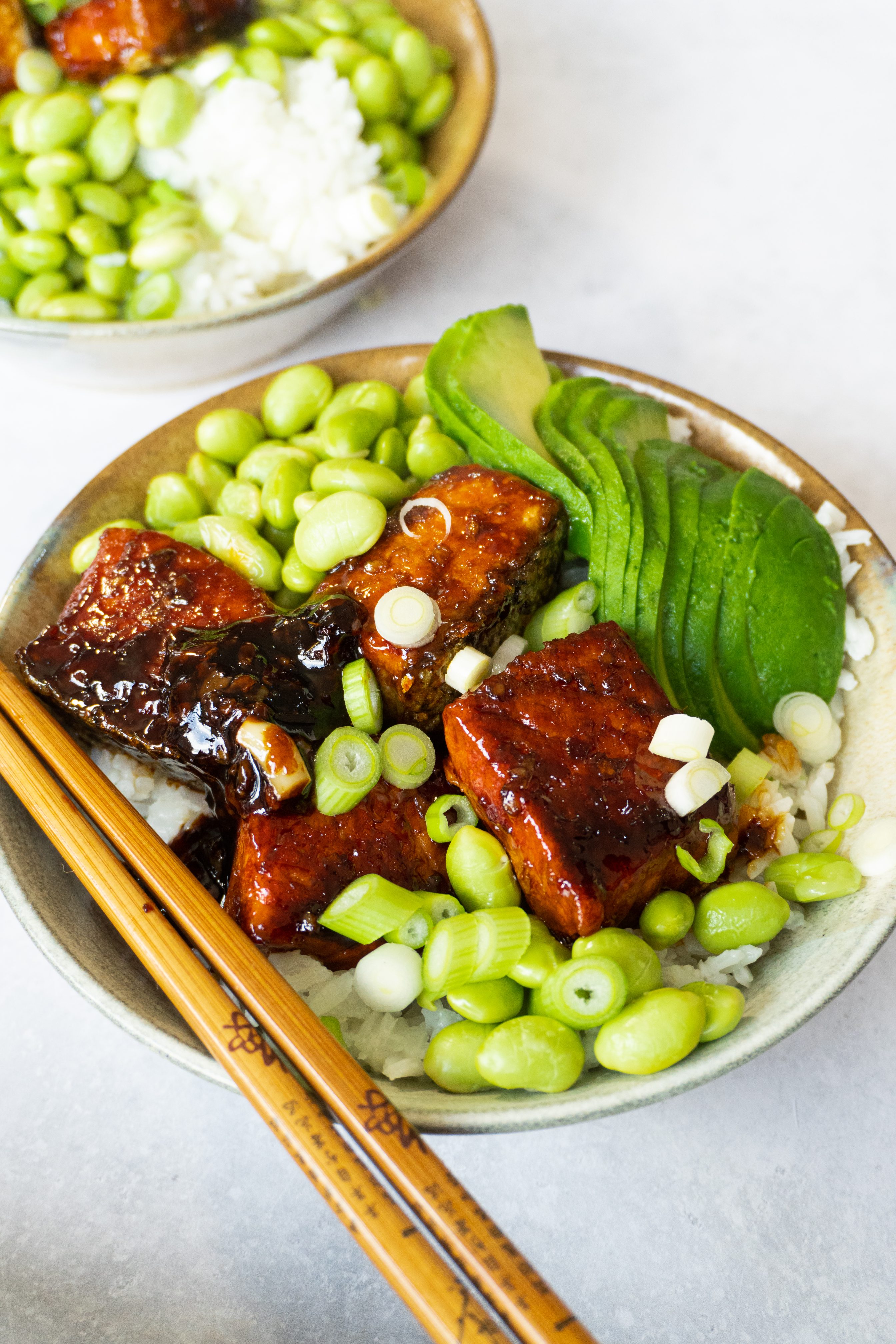 A side view of a Crispy Honey Ginger Garlic Salmon Bowl. The dish is served in a white bowl and features a bed of fluffy white rice topped with a crispy pan-seared salmon fillet