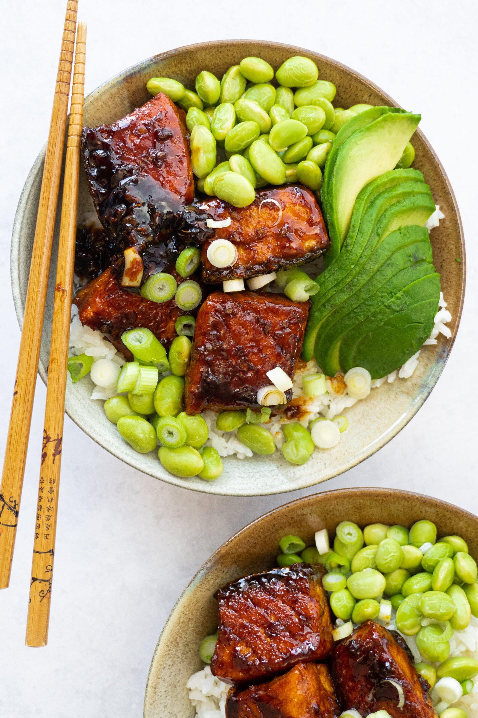 Perfectly glazed Crispy Honey Ginger Garlic Salmon Bowl ready to be served, garnished with edamame and spring onions
