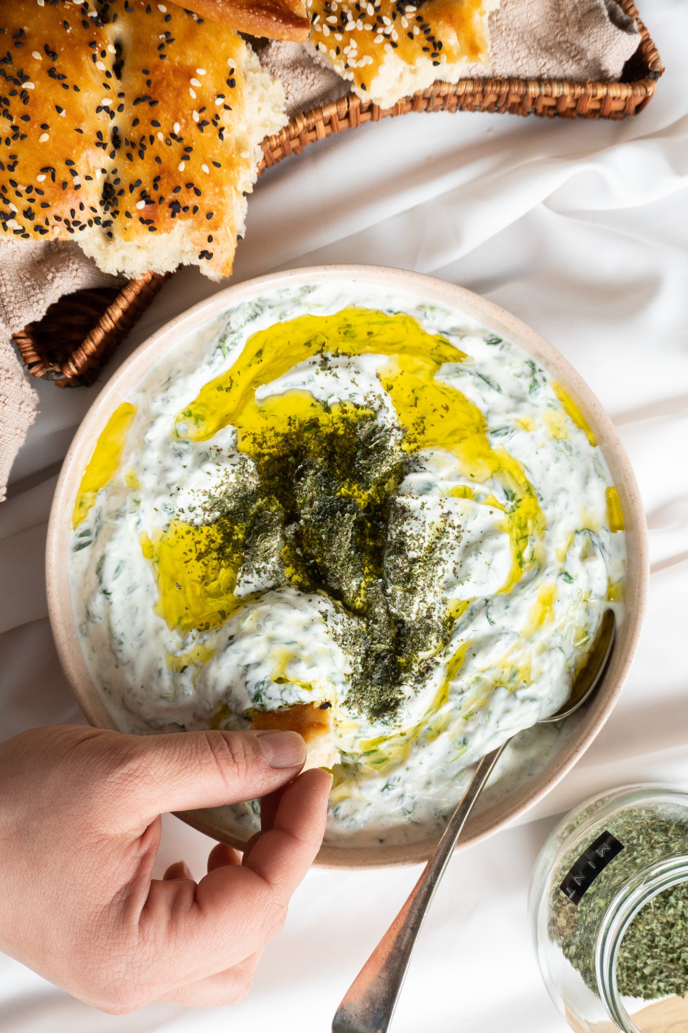 A bowl of Borani Esfenaj - Persian spinach yogurt dip a delicious and healthy Persian dip made with yogurt, spinach, and aromatic herbs. The dip has a vibrant green color and is served with crispy pita chips on the side.