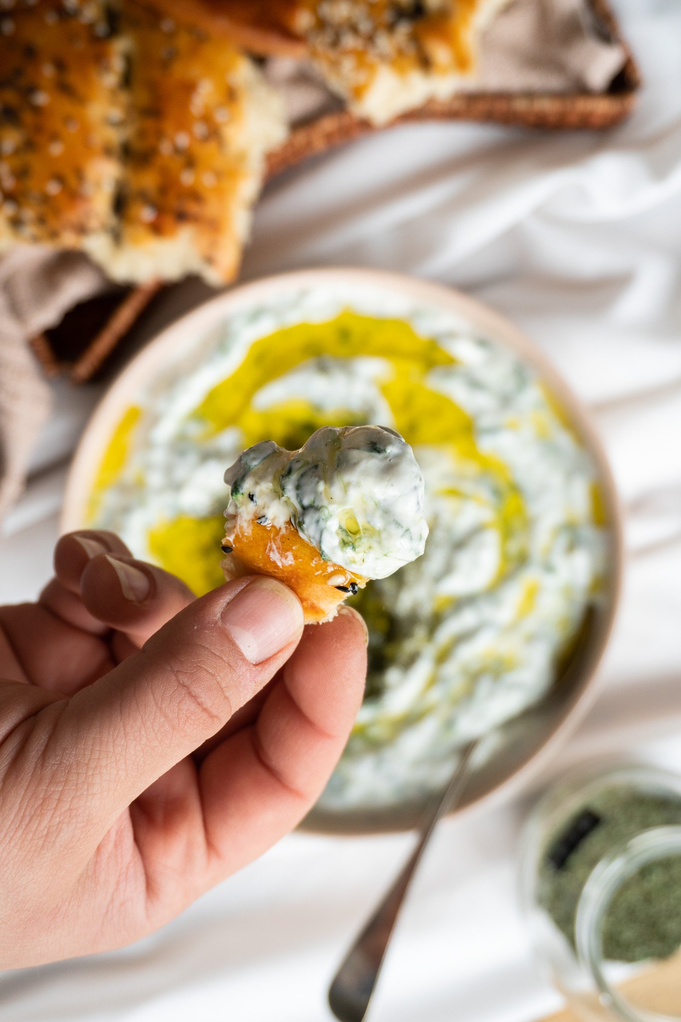A close-up of Borani Esfenaj, a creamy and refreshing yogurt dip that is popular in Iranian cuisine. The dip is made with spinach, garlic, and is garnished with dried mint leaves.