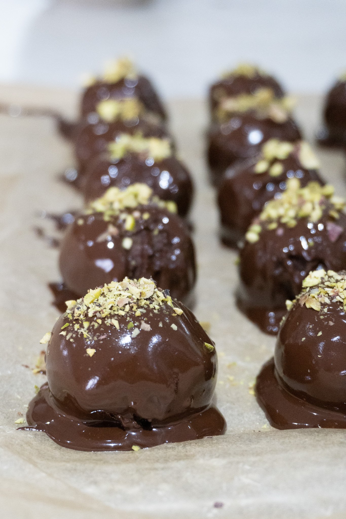 A bite-sized chocolate date truffle with a pistachio on top, perfect for a quick snack.