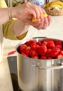 squeezing lemon juice in the pot of strawberry jam 