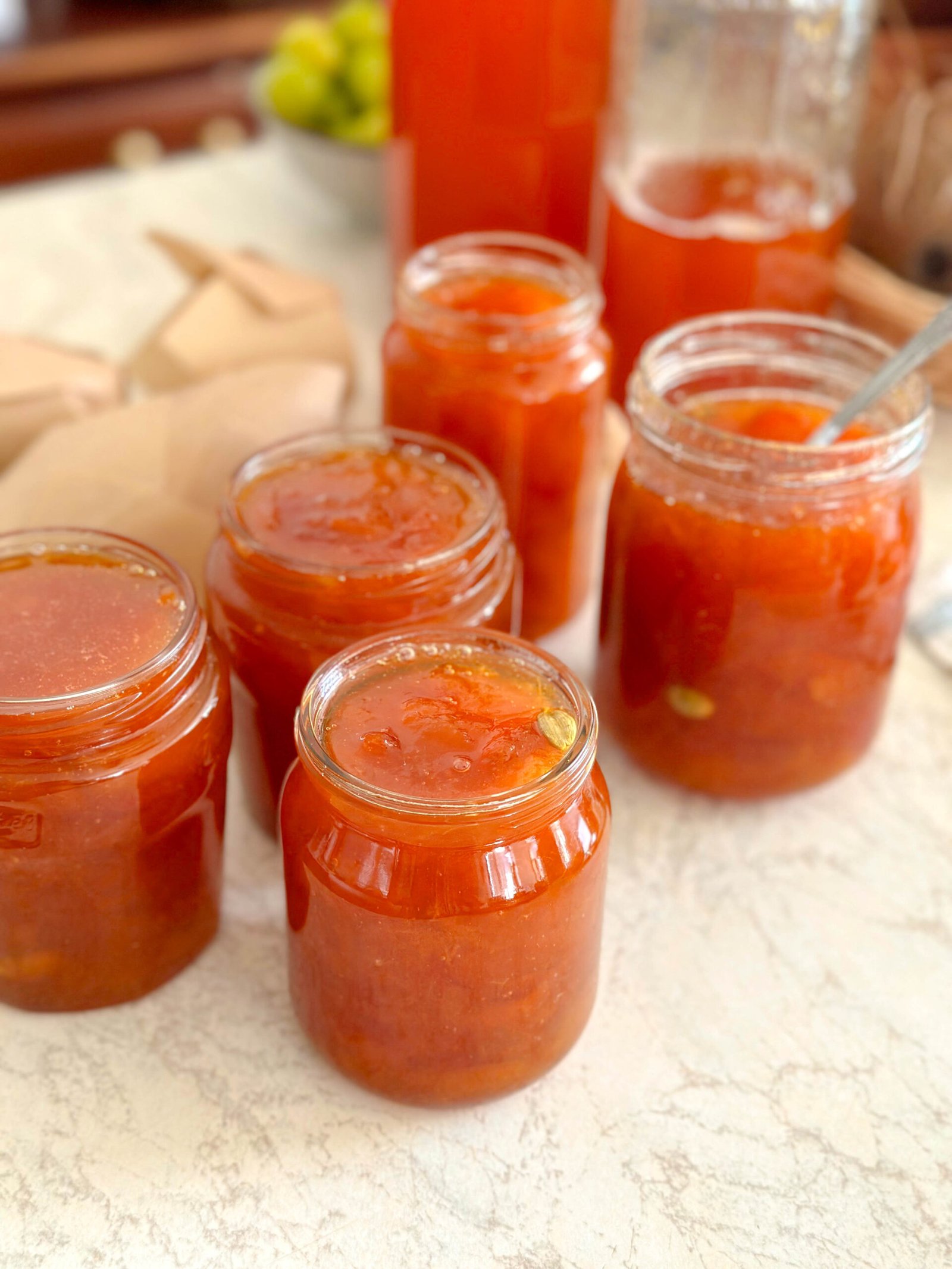 Several glass jars filled with golden apricot jam with cardamom, sealed and ready for storage or gifting.