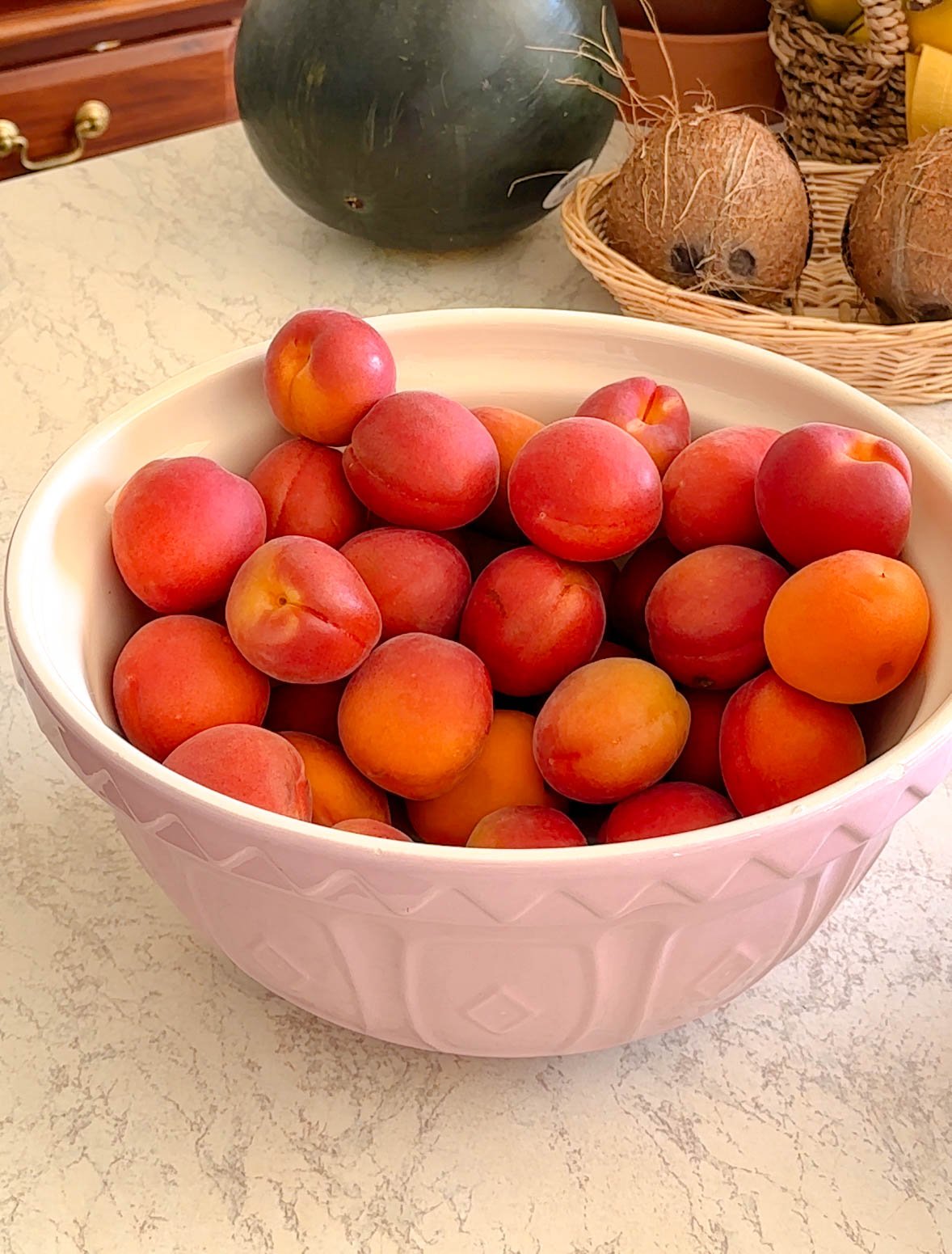 A bowl filled with ripe, fresh apricots, ready to be turned into homemade apricot jam with cardamom.