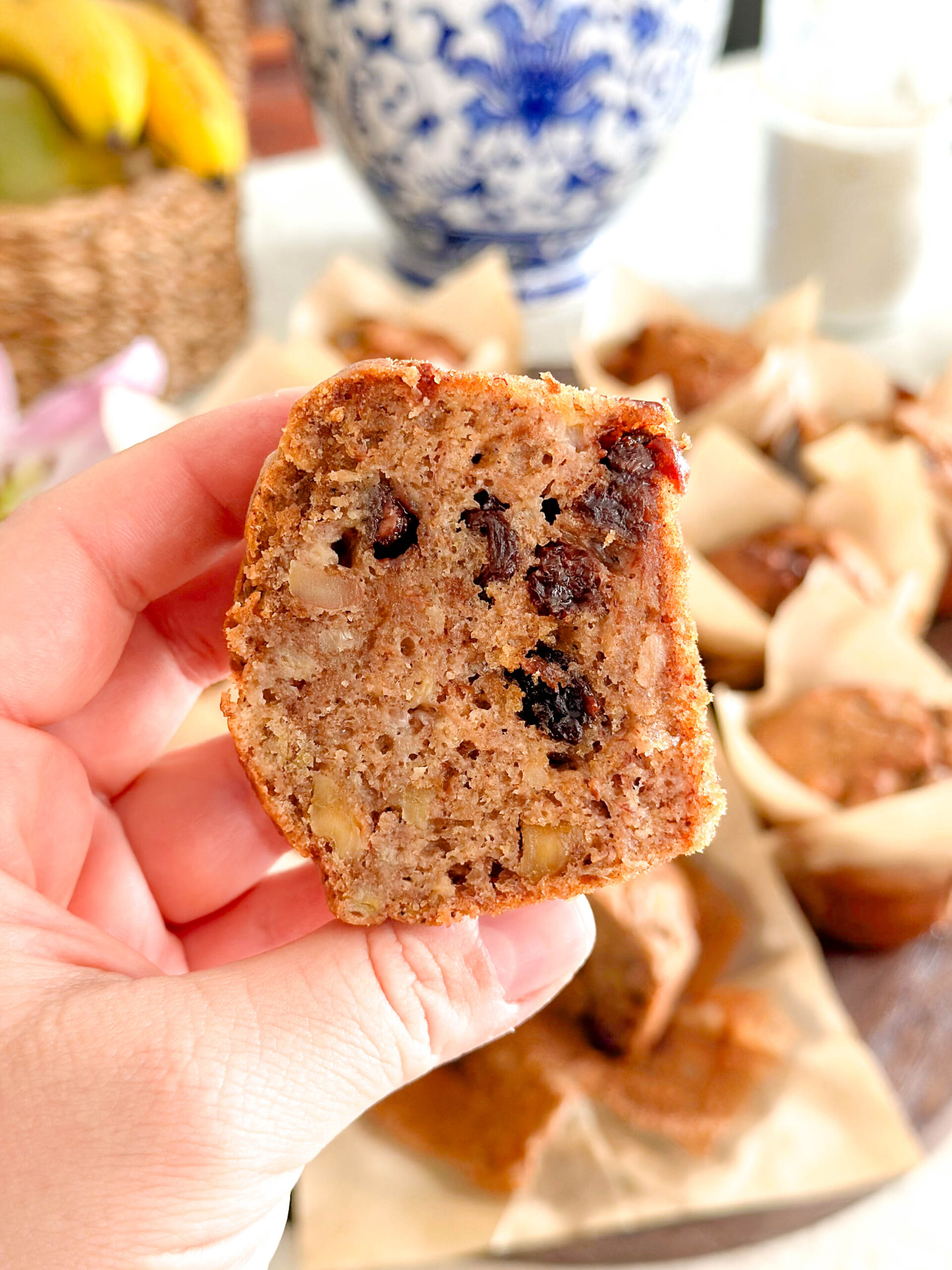 A Sourdough banana bread muffin cut in half and being held up to the camera showing the light, fluffy texture.