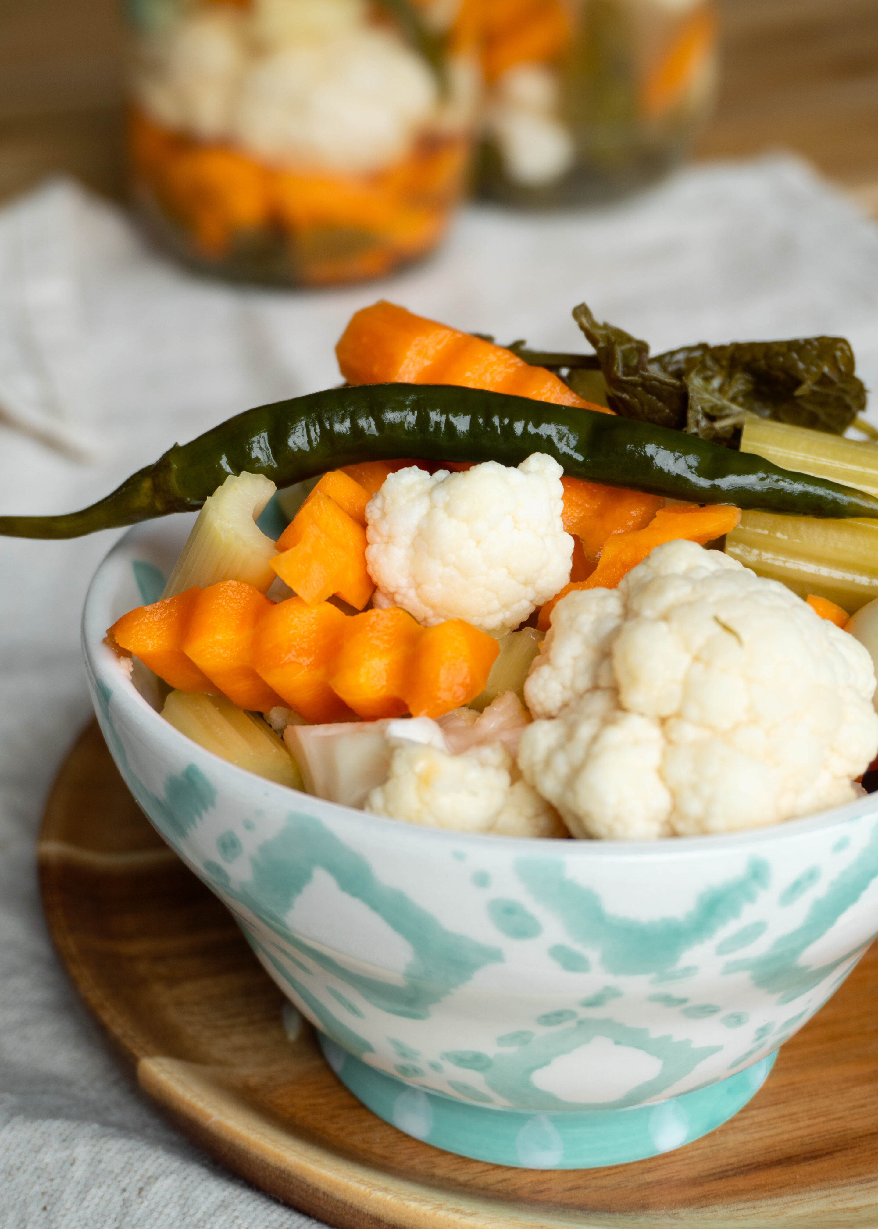 A bowl of Persian Torshi Shoor, ready to eat, with bright pickled red cabbage, orange carrots, green chilies, crunchy cauliflower, and celery sticks glistening in brine.