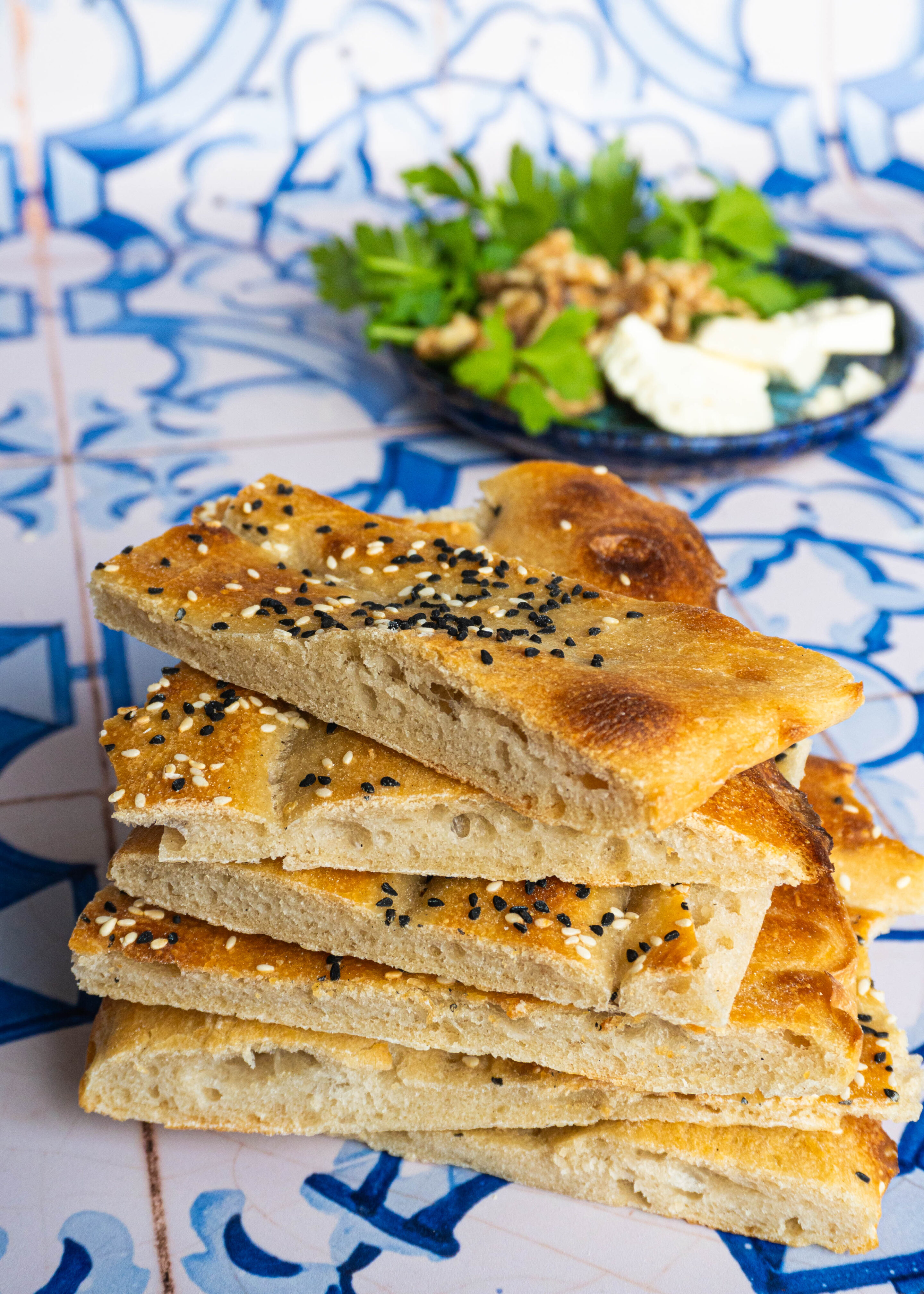 Close-up stack of sliced Barbari pieces, their airy crumb and delicate bubbles catching the light, showing the perfect balance between crisp crust and soft, pillowy interior.