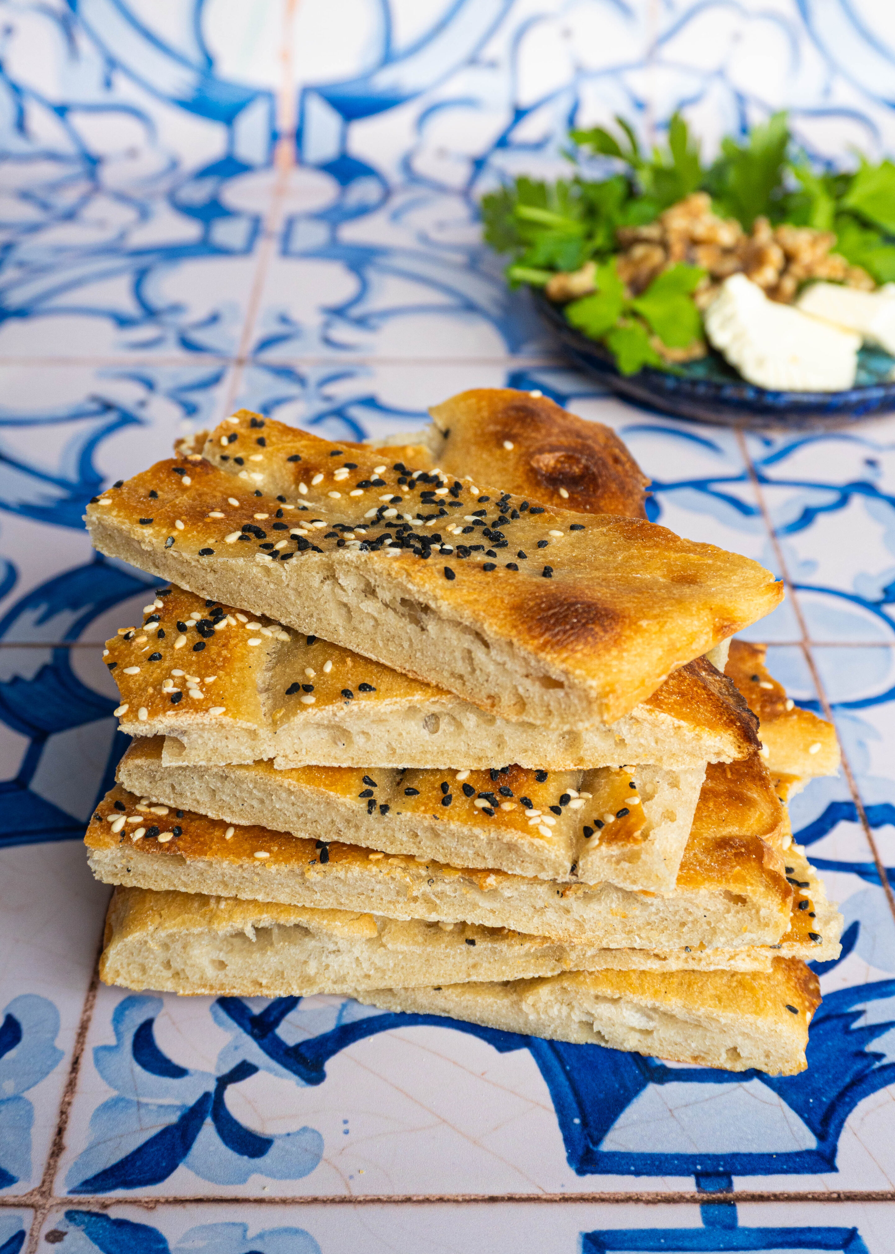 Close-up stack of sliced Barbari pieces, their airy crumb and delicate bubbles catching the light, showing the perfect balance between crisp crust and soft, pillowy interior.