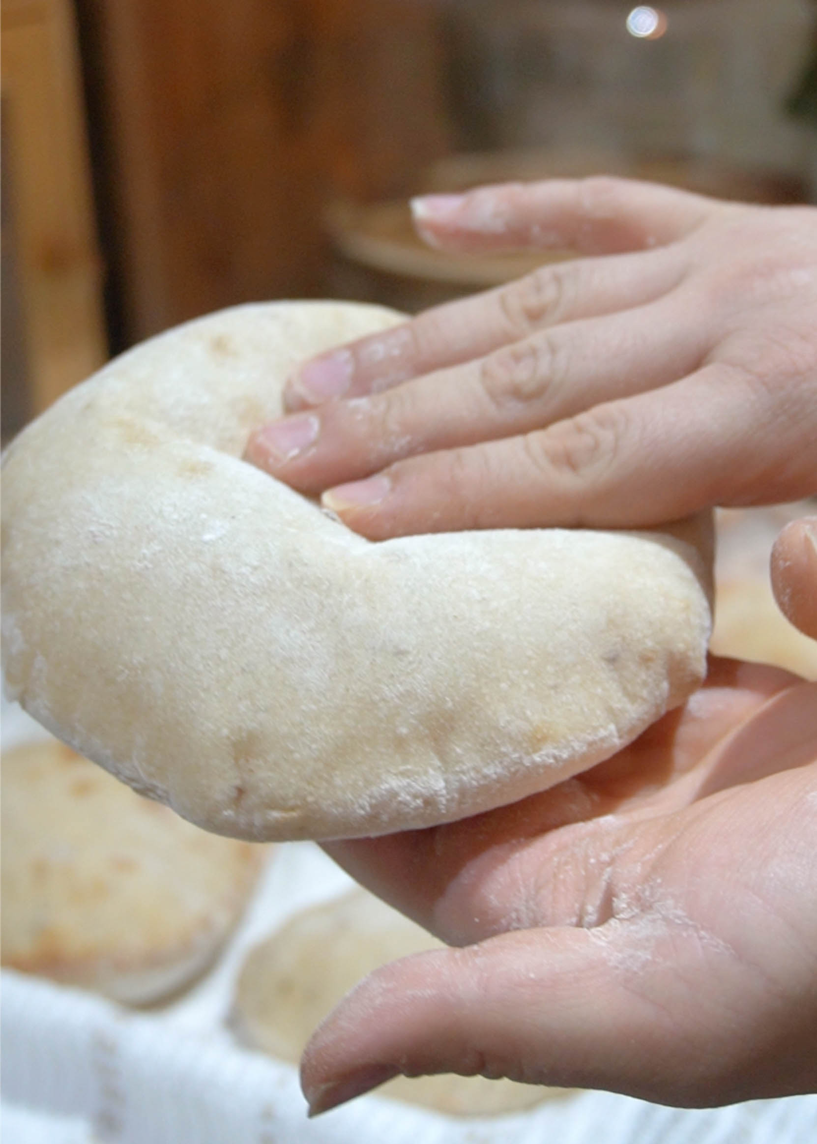 A freshly baked sourdough pita being squished in hand, revealing its ultra-soft, airy, and pillowy interior.