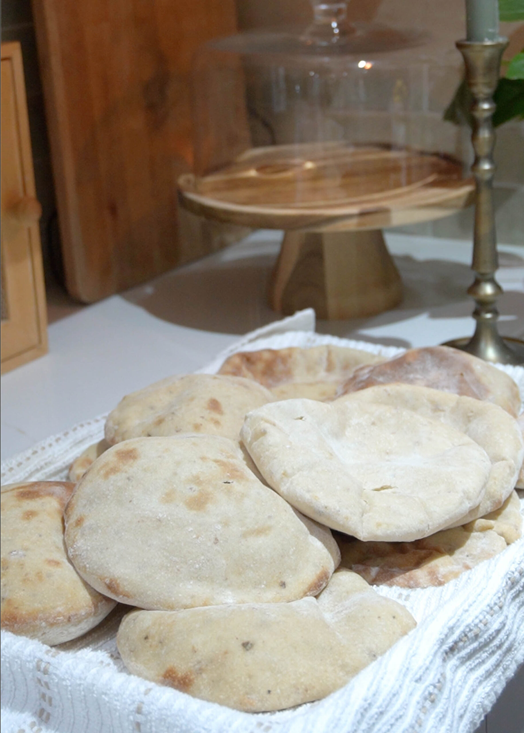 A tray of warm sourdough pita bread, freshly baked with golden, puffed tops, cooling on a baking sheet.