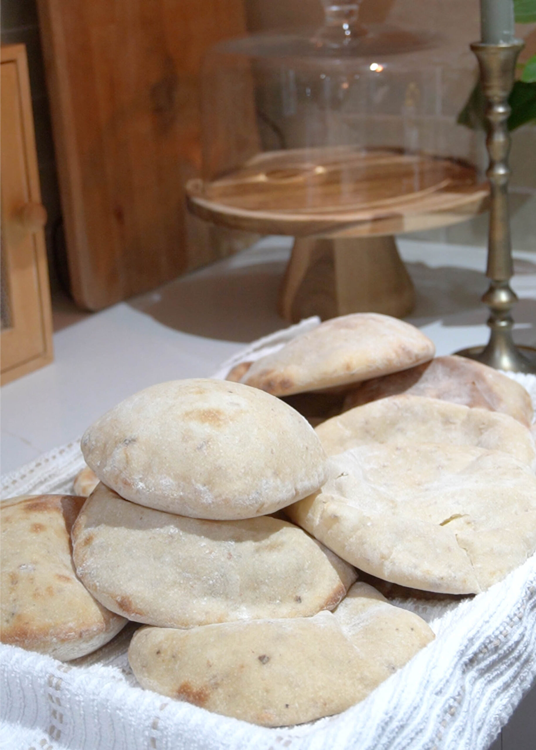 A tray of warm sourdough pita bread, freshly baked with golden, puffed tops, cooling on a baking sheet.