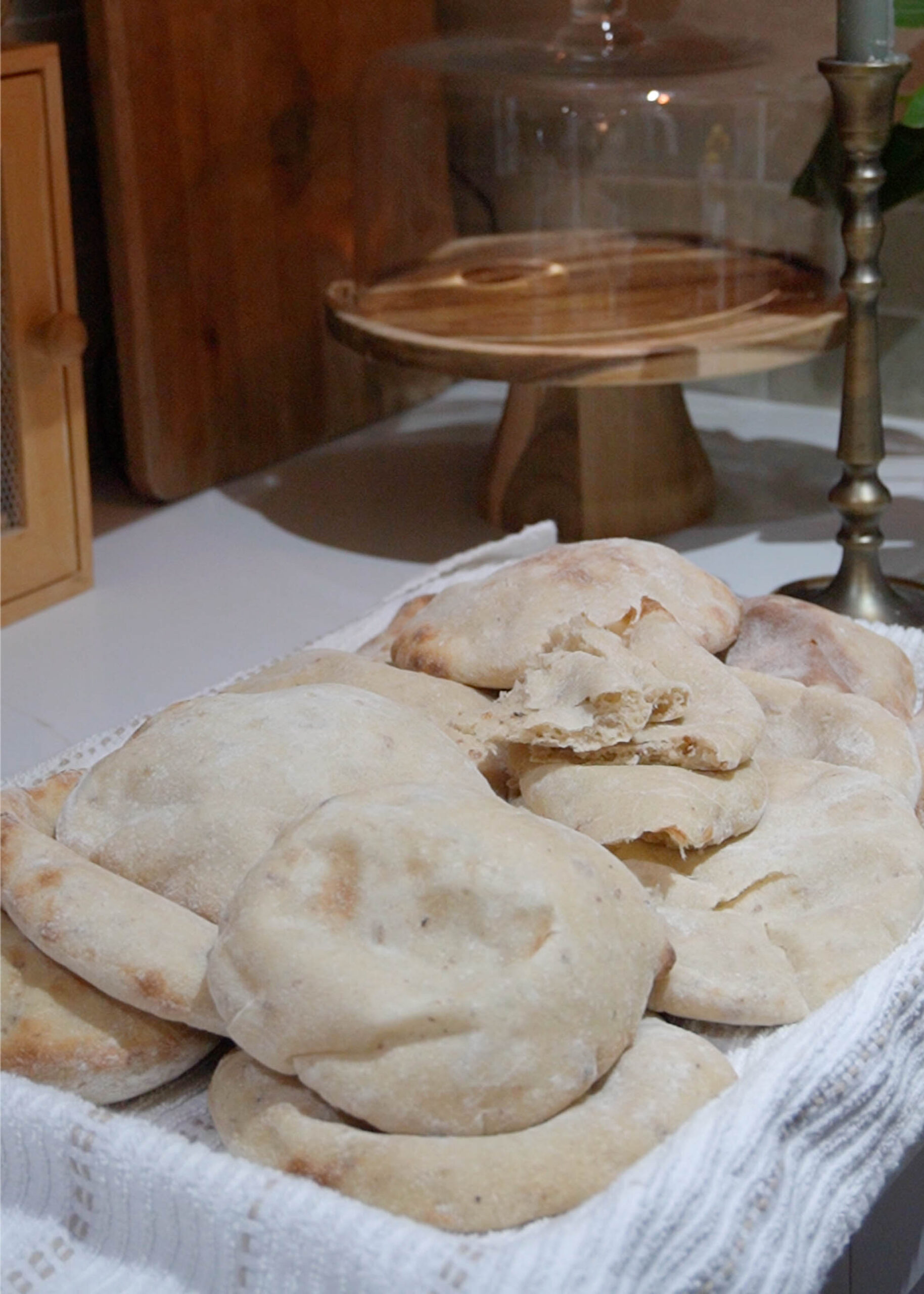 A tray of warm sourdough pita bread, freshly baked with golden, puffed tops, cooling on a baking sheet.