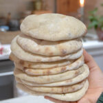 A stack of freshly baked Super Easy Sourdough Pita Bread, soft, fluffy, and slightly golden, ready to be served.