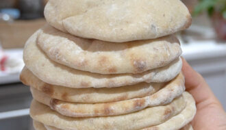 A stack of freshly baked Super Easy Sourdough Pita Bread, soft, fluffy, and slightly golden, ready to be served.