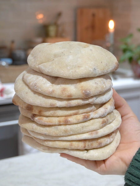 A stack of freshly baked Super Easy Sourdough Pita Bread, soft, fluffy, and slightly golden, ready to be served.