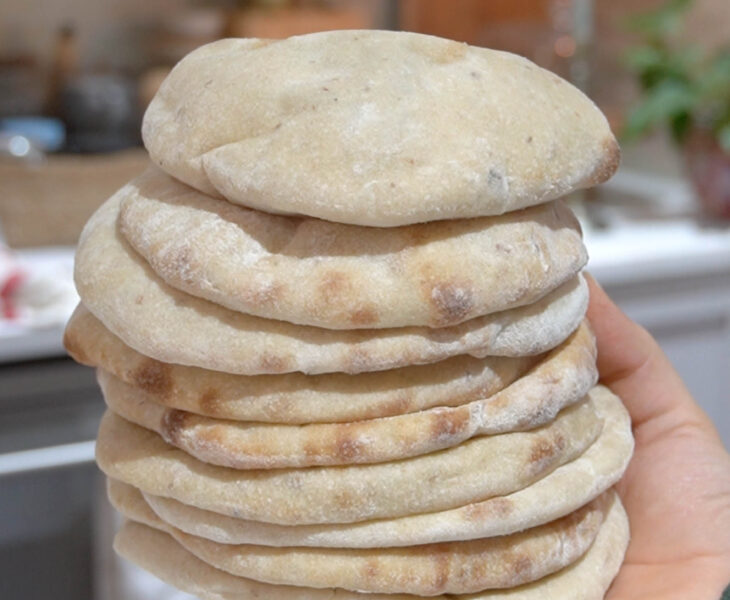 A stack of freshly baked Super Easy Sourdough Pita Bread, soft, fluffy, and slightly golden, ready to be served.