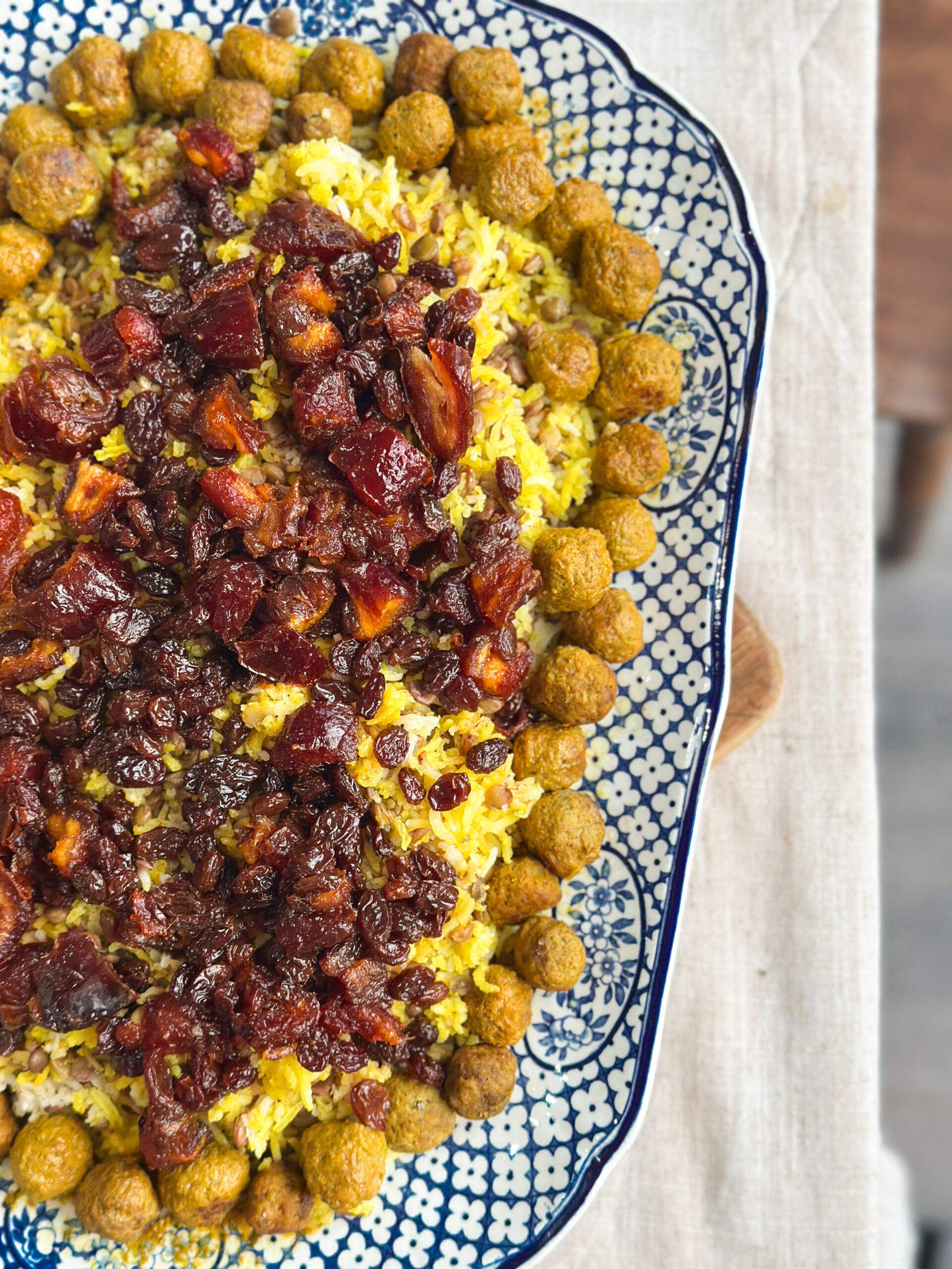 Adas Polo served with fresh herbs, yoghurt, and salad on a Persian-inspired table.