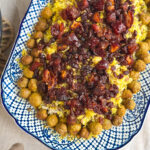 Close-up of Adas Polo, Persian lentil rice topped with spiced meatballs, caramelised dates, and sultanas, served on a rustic platter.