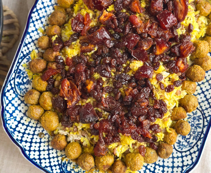 Close-up of Adas Polo, Persian lentil rice topped with spiced meatballs, caramelised dates, and sultanas, served on a rustic platter.