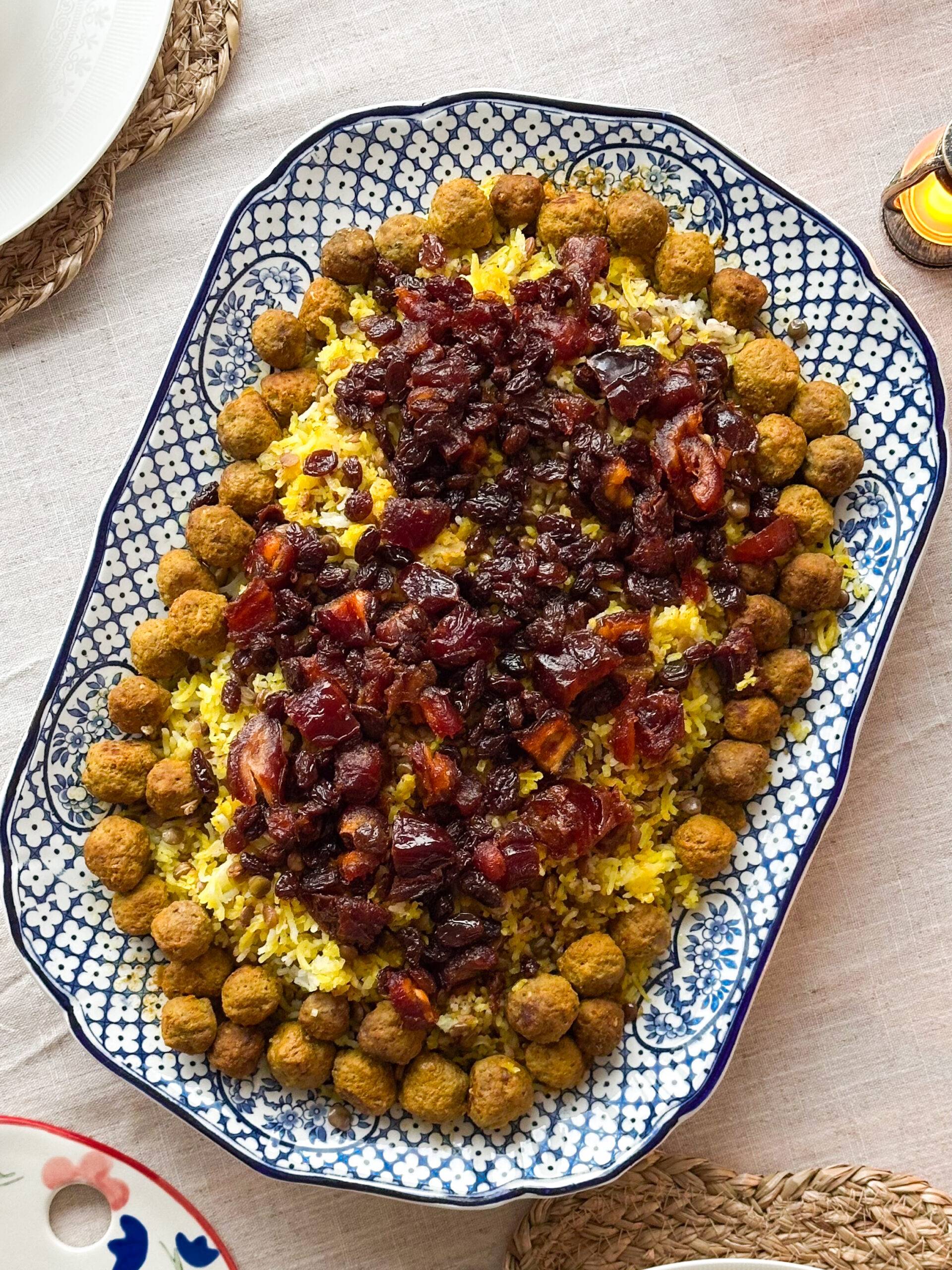 Adas Polo served with fresh herbs, yoghurt, and salad on a Persian-inspired table.